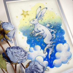 Photograph of a matted print of a colored pencil and graphite drawing of a white yule hare with wispy long fur coming from it’s ears, paws, and tail. The hare is floating in profile facing to the left, hovering over 3 large clouds against the gradient of a blue and yellow night sky in the background. The gradient of the sky is in a cloudy shape that frames the clouds and the yule hare. Tiny yellow stars and white snowflakes are scattered around the scene. The hare's head is looking up towards a bright yellow star to the left with a stoic expression. The mat-board is white on the top layer and silver on the second layer. Blue roses rest on top of the print to the left. A small silver stamp with the Terratoff icon is at the bottom left corner of the print, under the roses.