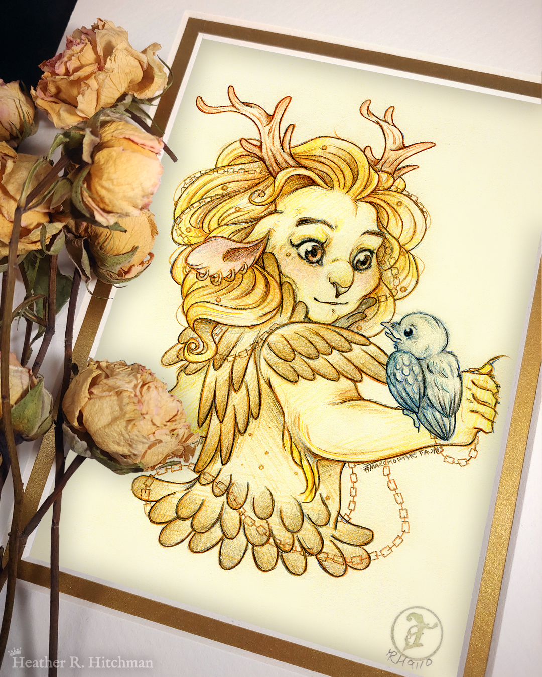 Photograph of a matted print of a graphite and colored pencil hips up portrait drawing of a child female faun with golden fur, orange eyes, and branch like antlers. The faun is wearing golden armor that looks like feathers, and has copper chains woven through her golden mane that flow around her body. She has four gold hoop piercings in her right ear, and a tiny golden stud piercing below the outside corner of her right eye. The faun stands with her back to the viewer, looking over her right shoulder at a small raven hatchling that stands on her right arm. The raven looks up at the faun with a happy expression. The faun looks back at the raven with a subdued pleasantly surprised expression. The faun child looks youthful, and yet has undeniable strong bone structure that makes her look somewhat like a lioness in the face. The mat-board is white on the top layer and gold on the second layer. Yellow roses rest on top of the print to the left. A small gold stamp with the Terratoff icon is at the bottom right corner of the print.