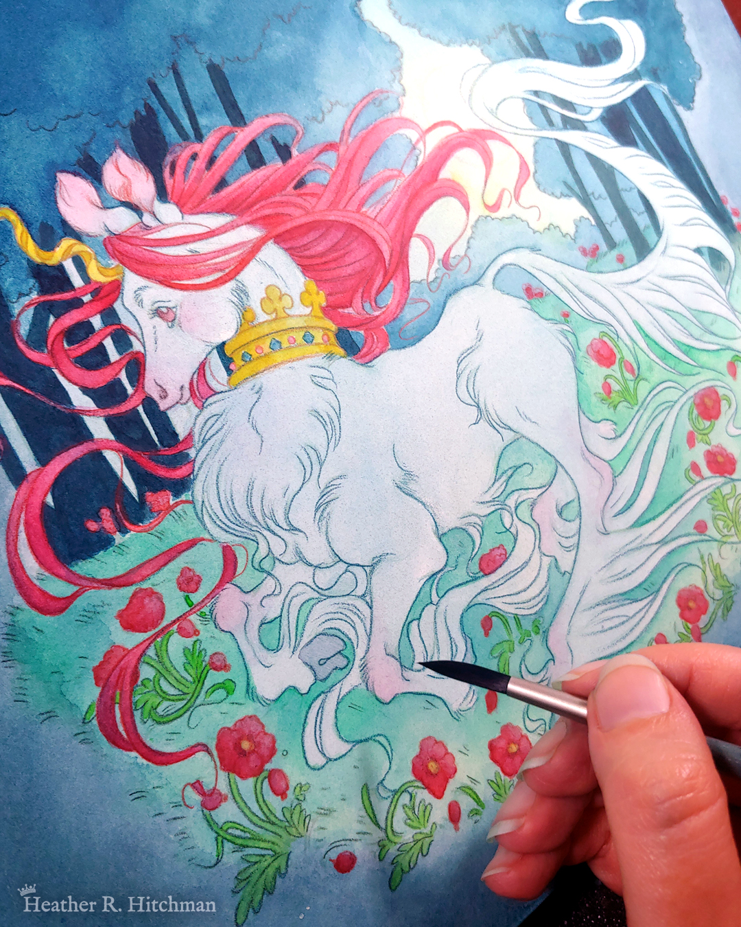 Process photograph of a full body watercolor, gouache, and colored pencil painting of a unicorn running through a moonlit forest. The artist’s hand is resting on the bottom right section of the painting holding a paintbrush. The painting is loose and sketchy with soft layers of watercolors and colored pencils created so far. The unicorn has light blue fur that flows in elegant tufts from their chest, ankles, and lion-like tail. He has a mane of raspberry red that swirls around in the wind behind the unicorn’s head. The unicorn has a twisting golden horn, and wears a golden crown encrusted with red and blue jewels around their neck. Running in profile to the left with their front hooves close to their chest, the unicorn has a peaceful expression on its face. The background is a cool greenish blue night forest scene. In the field red poppies bloom under the unicorn’s hooves. Trees with dark branches are in the far background, with an opening behind the unicorn that reveals a large full moon glowing white.
