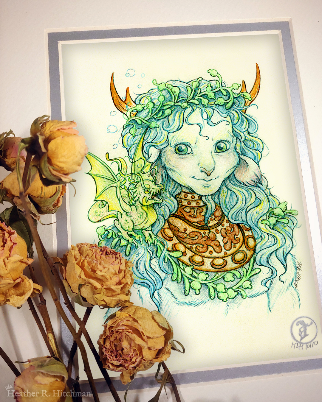 Photograph of a matted print of a graphite and colored pencil chest up portrait drawing of a male faun with teal hair and small pointed wood antlers. The faun is facing ¾ to the right and wears the copper collar of an old diving helmet around his neck like a necklace. His long wavy hair looks wet and has strands of green seaweed entangled around his crown and chest. The faun’s build is muscular yet lean, with defined cheekbones and striking green eyes. The faun is looking over to the left with a smirk on his face towards a small green water dragon perched on his shoulder. The water dragon is lifting it’s wings into the air with excitement looking back at the faun. The mat-board is white on the top layer and silver on the second layer. Yellow roses rest on top of the print to the left. A small silver stamp with the Terratoff icon is at the bottom right corner of the print.