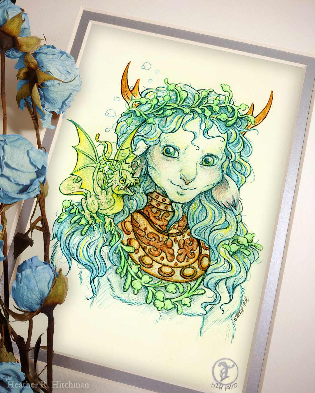 Photograph of a matted print of a graphite and colored pencil chest up portrait drawing of a male faun with teal hair and small pointed wood antlers. The faun is facing ¾ to the right and wears the copper collar of an old diving helmet around his neck like a necklace. His long wavy hair looks wet and has strands of green seaweed entangled around his crown and chest. The faun’s build is muscular yet lean, with defined cheekbones and striking green eyes. The faun is looking over to the left with a smirk on his face towards a small green water dragon perched on his shoulder. The water dragon is lifting it’s wings into the air with excitement looking back at the faun. The mat-board is white on the top layer and silver on the second layer. Blue roses rest on top of the print to the left. A small silver stamp with the Terratoff icon is at the bottom right corner of the print.