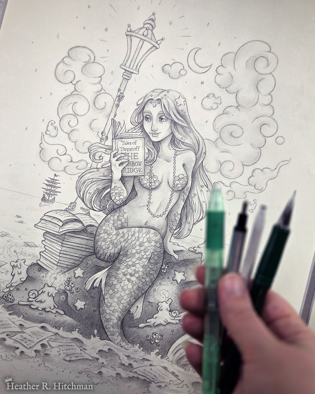 Artist holding pencils over black and white graphite full body drawing of a mermaid reading a book under the moonlight while sitting on a rock in the middle of the sea. The rock is covered in glowing candles and also has a pile of books besides the mermaid’s tail. An old fashioned street lantern covered in barnacles is attached to the rock, illuminating the night around the mermaid’s face. Gentle waves wash up against the rock. Loose pages from books float in the water into the distance, leading towards a mysterious ship that vanishes into the night. Puffy fish shaped clouds fill the nigh sky surrounding a crescent moon. The mermaid is holding a book in her right hand up to her face. Her other hand is placed behind her as she leans back slightly, her left arm supporting her weight. Her body faces the viewer, and she has a peaceful smile as she looks towards the book and reads.