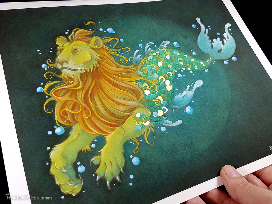 Photograph of a print of a watercolor, gouache and colored pencil full body painting of a mermaid lion under the sea surrounded by blue bubbles. Also known as a merlion, the creature has the torso and front legs of a golden lion and the tail of a fish. The merlion is swimming to the left at a ¾ angle with a tranquil expression on its face. He has bright orange eyes, a flowing orange gold mane, and yellowish gold fur. His tail hovers behind him, covered in gold and green scales of every shade. The merlion’s fins and tail fin are a soft green color that fades to white on the edges. In the background the waters are a deep teal green with a lighter circle of green directly behind the merlion. The print has a ½ inch white border around the edges. The fingertips of the artist’s hand can be seen holding the print in the bottom right corner.