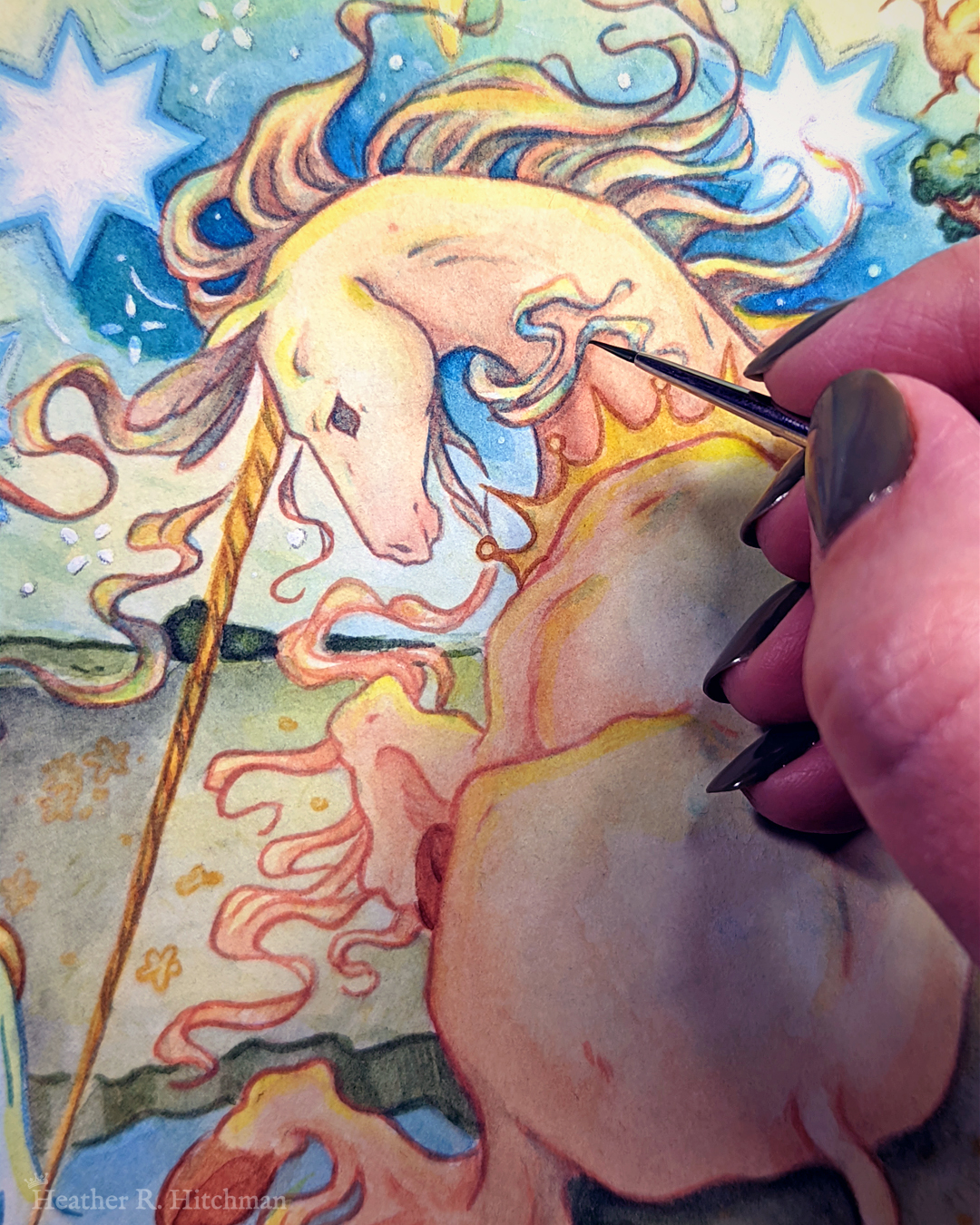 Process photo of a loose watercolor and gouache painting of a unicorn sitting by a lake under a night sky. The unicorn is white and wearing a golden crown. The artist’s hand is painting the unicorns hair. The hand is to the right of the image.