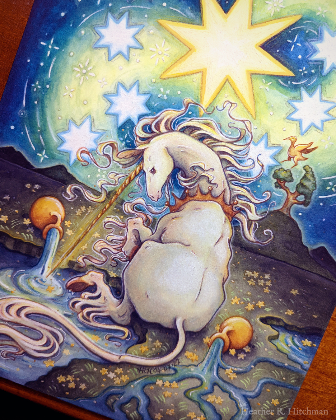 Watercolor and gouache painting of a unicorn sitting by a lake under a night sky. The sky is dark blue and filled with tiny white stars. Seven large white stars surround a massive yellow star in the center of the sky. A swirl of bright yellow light weaves upwards towards the heavens, illuminating the scene below. The unicorn sits in front of a landscape scene, with green mountaintops in the background. On one of the mountaintops a small tree grows, on top of the branches a yellow ibis bird flaps its wings. The unicorn is sitting with its back towards the viewer, the head turned in profile as she dips her long golden horn into the lake to the left of the image. The unicorn wears a golden crown around her neck. Two golden urns rest on their sides on the ground, spilling water onto the grassy scene that trickles into the lake waters.