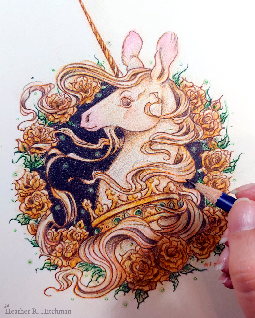 Process photograph of a graphite and colored pencil portrait drawing of a light gold colored royal unicorn bust framed in a circular wreath of golden roses. The background inside of the wreath behind the unicorn is black with tiny orbs of green light floating around. Outside of the wreath the portrait has a sepia background color. The unicorn lifts her head in profile facing to the left with a peaceful expression on her face. He has a flowing gold and pink mane and chin beard, light golden fur, and a long golden horn in the center of her forehead. The unicorn wears a large crown of green jewels around her neck. The artist’s fingertips are in the lower right corner holding the tip of a graphite pencil over the artwork.