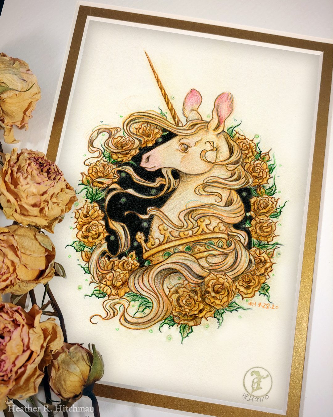 Photograph of a matted print of a graphite and colored pencil portrait drawing of a light gold colored royal unicorn bust framed in a circular wreath of golden roses. The background inside of the wreath behind the unicorn is black with tiny orbs of green light floating around. Outside of the wreath the portrait has a sepia background color. The unicorn lifts her head in profile facing to the left with a peaceful expression on her face. He has a flowing gold and pink mane and chin beard, light golden fur, and a long golden horn in the center of her forehead. The unicorn wears a large crown of green jewels around her neck. Yellow roses rest on top of the print to the left. A small gold stamp with the Terratoff icon is at the bottom right corner of the print.