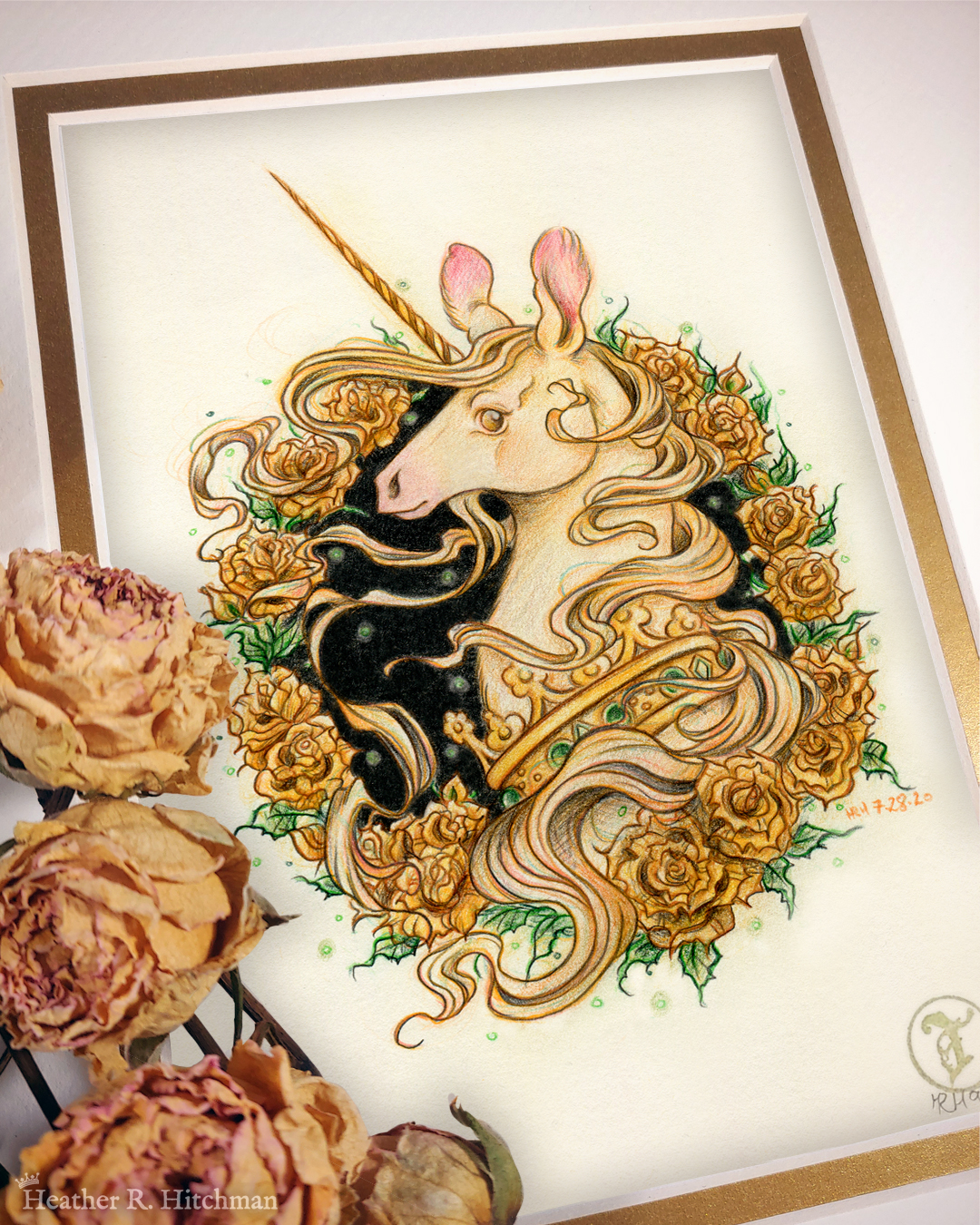 Photograph of a matted print of a graphite and colored pencil portrait drawing of a light gold colored royal unicorn bust framed in a circular wreath of golden roses. The background inside of the wreath behind the unicorn is black with tiny orbs of green light floating around. Outside of the wreath the portrait has a sepia background color. The unicorn lifts her head in profile facing to the left with a peaceful expression on her face. He has a flowing gold and pink mane and chin beard, light golden fur, and a long golden horn in the center of her forehead. The unicorn wears a large crown of green jewels around her neck. Yellow roses rest on top of the print to the left. A small gold stamp with the Terratoff icon is at the bottom right corner of the print.