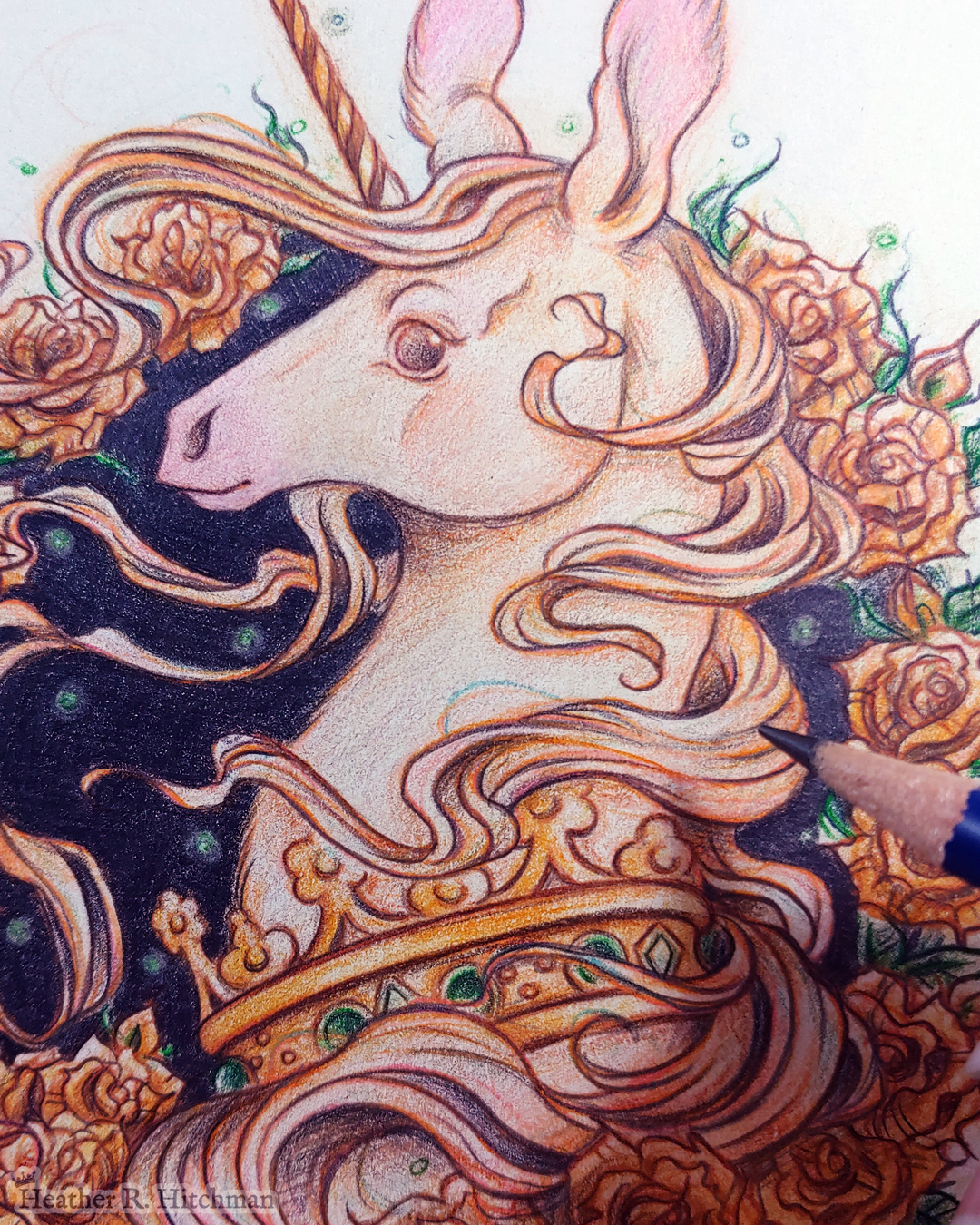 Close up process photograph of a graphite and colored pencil portrait drawing of a light gold colored royal unicorn bust framed in a circular wreath of golden roses. The background inside of the wreath behind the unicorn is black with tiny orbs of green light floating around. Outside of the wreath the portrait has a sepia background color. The unicorn lifts her head in profile facing to the left with a peaceful expression on her face. He has a flowing gold and pink mane and chin beard, light golden fur, and a long golden horn in the center of her forehead. The unicorn wears a large crown of green jewels around her neck. The tip of a graphite pencil hovers over the artwork to the right.