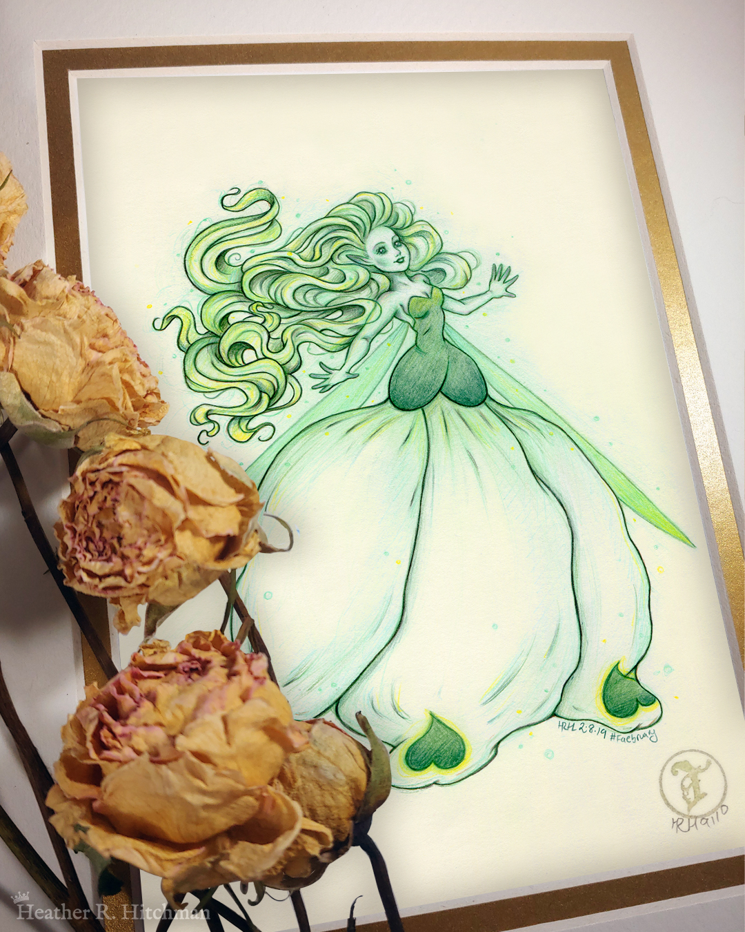 Photograph of a matted print of a colored pencil and graphite full body drawing of a seelie snowdrop fae. The fae faces ¾ to the right, her arms outstretched to each side and her greenish white hair billowing behind her in a heap of floating curls. The fae wears a white and green ballgown shaped like a closed upside down snowdrop blossom. She has long narrow green wings that are angled downward behind her. The fae has a round childish face, with tiny black lips and large green eyes. She looks upward and to the right with a hopeful expression on her face. The mat-board is white on the top layer and gold on the second layer. Yellow roses rest on top of the print to the left. A small gold stamp with the Terratoff icon is at the bottom right corner of the print.