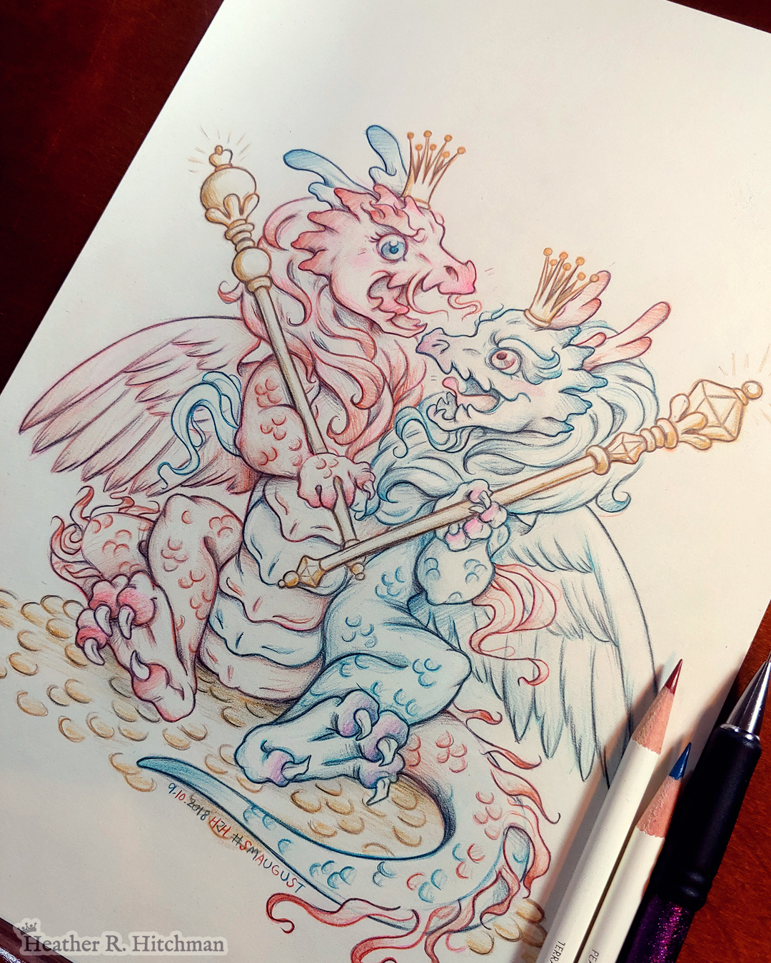 Photograph of a colored pencil and graphite drawing of a baby 2 headed hydra dragon. The left head and side of the dragon is red, the right head and side of the dragon is blue. The hydra sits upright on its butt facing the front on top of a pile of golden coins. The hind legs are spread forward while each arm holds a golden scepter in it’s claws. The two heads are arguing over the gold and treasure the hydra sits upon. Each head wears a golden crown on their head. The red head on the left has an angry roaring expression. The blue head on the right smiles mockingly. The hydra has a set of feathered wings like a bird, the left wing red and the right wing blue. The drawing is resting on a wooden desk. 3 pencils are laying over top of the drawing on the right side.