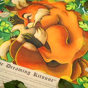 Photograph of a watercolor, gouache, ink, and colored pencil painting print of a sleeping fox with many tails known as a “kitsune”. The kitsune has golden orange fur, with white fur around his muzzle, eyes, and on the tips of his tails. His ears and paws have darker brown fur, and he appears to have 4 tails that are coiling around his feet. The kitsune is laying on his side with his front paws under his head like a pillow. He is coiling himself up in a cozy ball facing in profile to the left. The kitsune is sleeping with a tranquil expression on his face. He is laying on a green grass background surrounded by white branches and falling green leaves. Orbs of yellow light dance around the sleeping creature. 3 large fireflies are hovering in the scene, one in front of his face reaching for his ear, one by his shoulder, and the third by the base of his tails. Their rear ends are glowing with bright warm light. The print has a white border around it, and is surrounded by dried tree leaves. A scroll of parchment paper with a story printed on it in black in rests on top of the bottom left corner of the print.